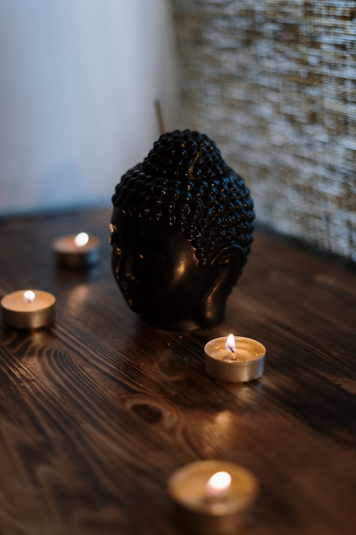 services-01 A serene setup with a Buddha head sculpture surrounded by soothing candlelight, perfect for relaxation.