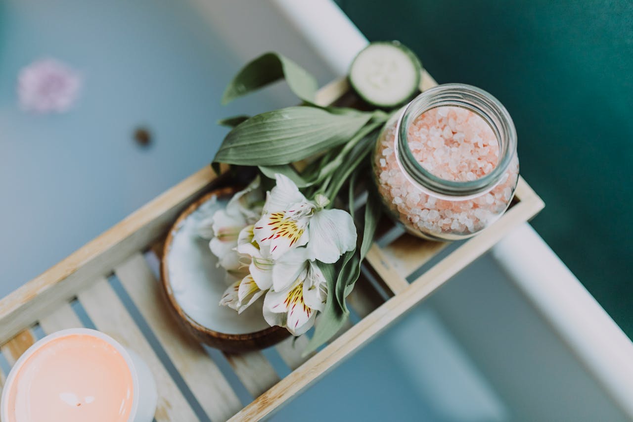 our-journey-03 Spa essentials on a tray with Himalayan salt, flowers, and candles for a relaxing bath.
